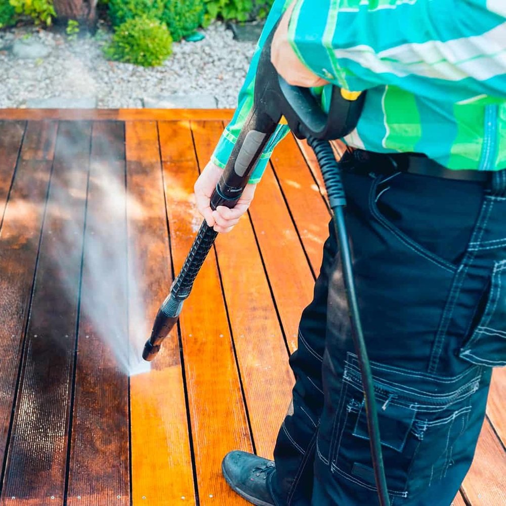Crew cleaning algae-stained patio and walkway outside occupied suburban home